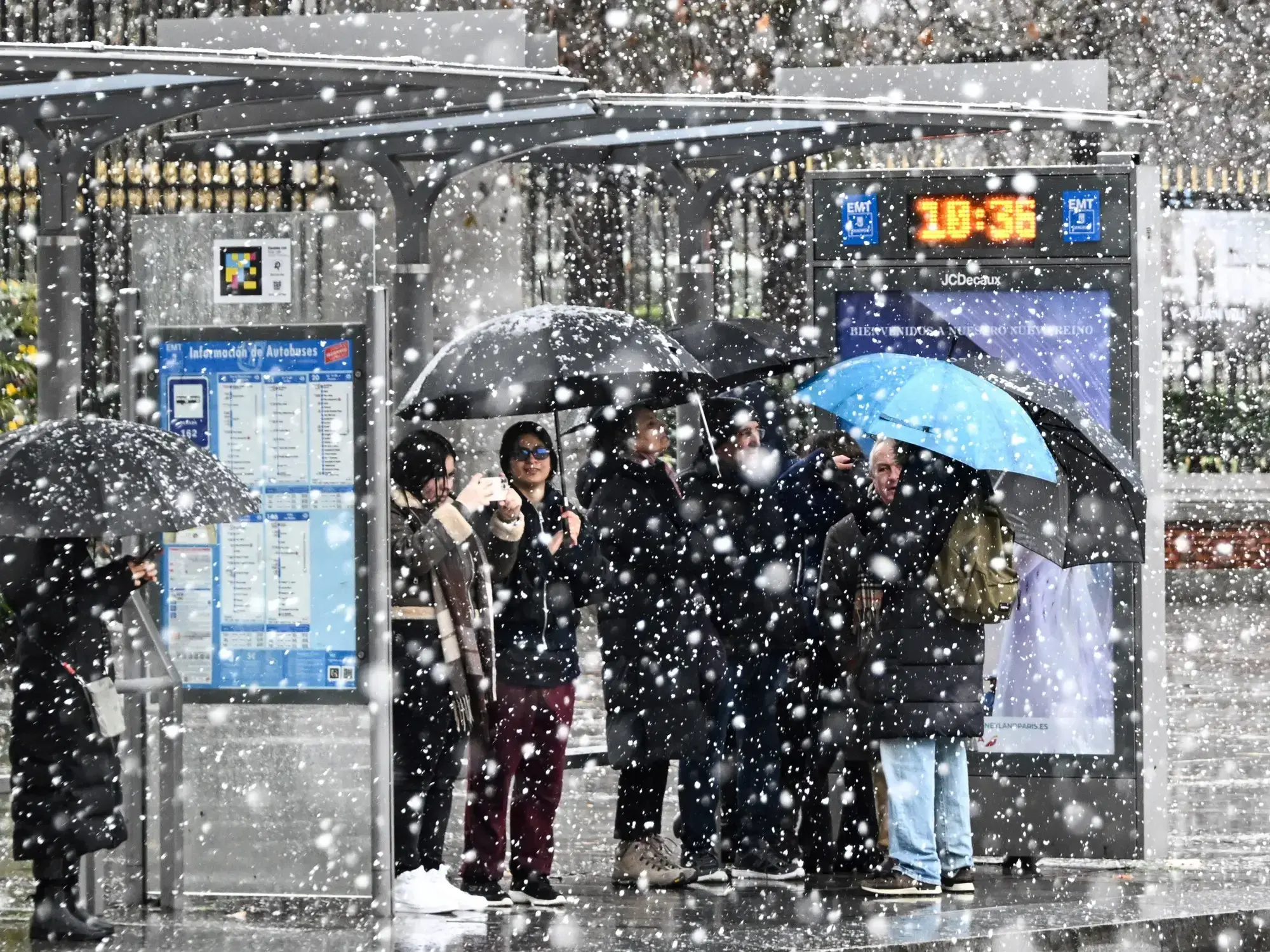 Una persona utiliza su teléfono celular frente a un muñeco de nieve en las afueras de Madrid.