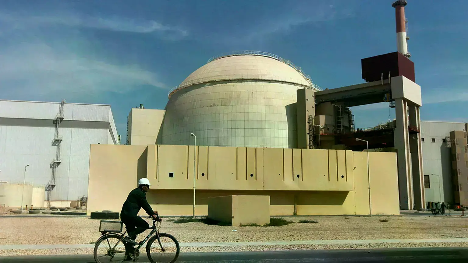 Un trabajador circula en bicicleta frente al edificio del reactor de la central nuclear de Bushehr.