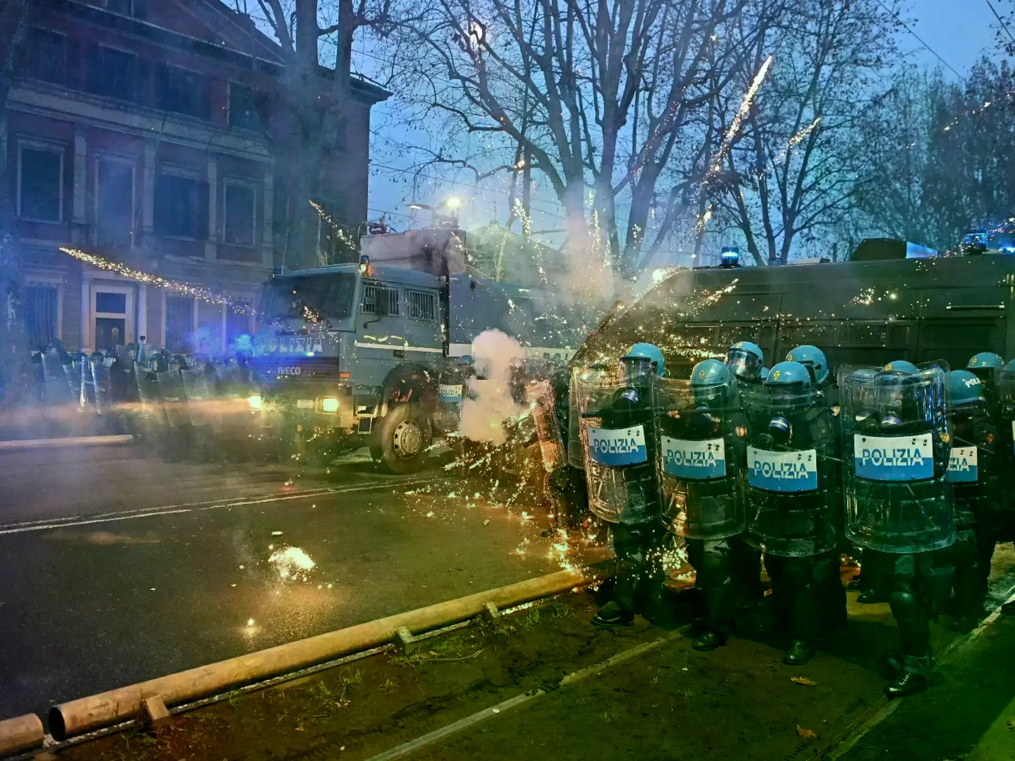 Manifestantes encapuchados enfrentándose a la policía en las calles de Turín.