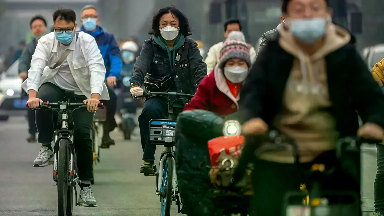 Vagabundos con mascarillas circulan en bicicleta por una calle del distrito financiero central de Pekín.