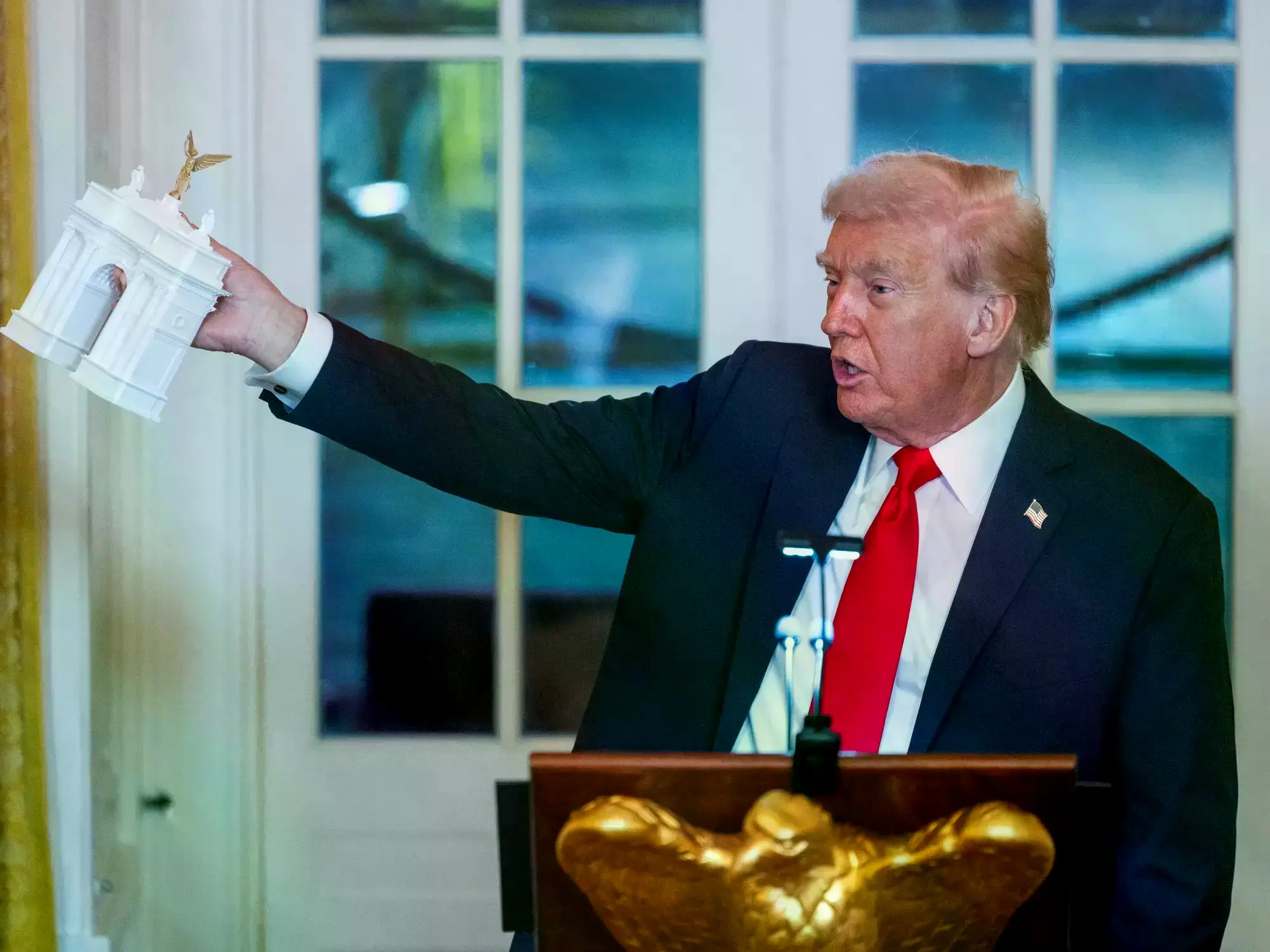 Donald Trump sostiene una maqueta del Arco del Triunfo durante una recepción en la Casa Blanca.