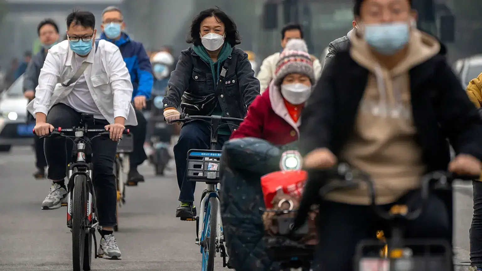 Personas con mascarillas circulan en bicicleta por el distrito financiero de Pekín.