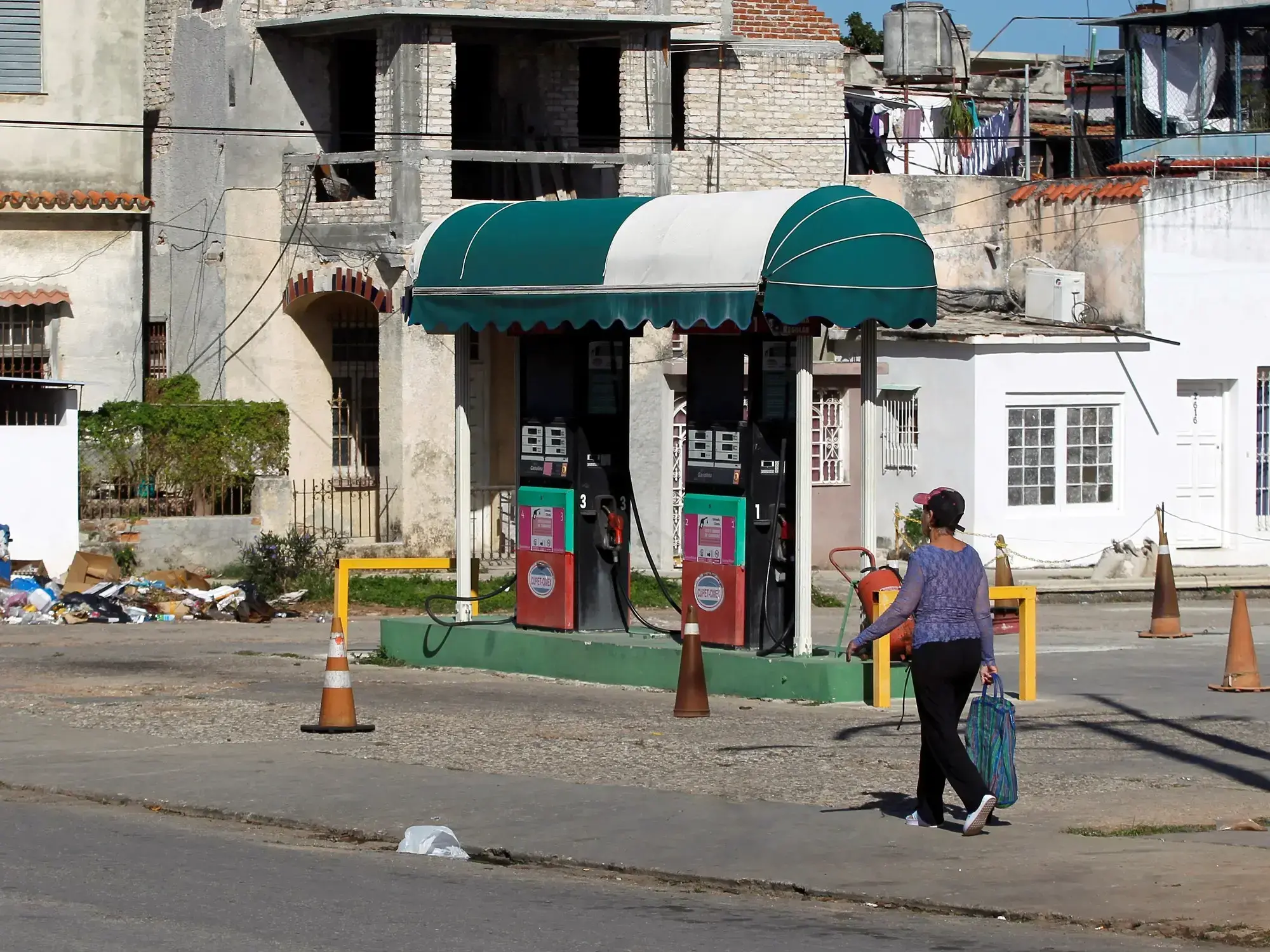 Personas caminan frente a una estación de servicio cerrada por falta de combustible en La Habana.
