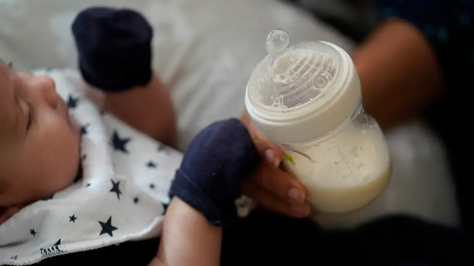 Una mujer sostiene un biberón de leche infantil mientras alimenta a su bebé.