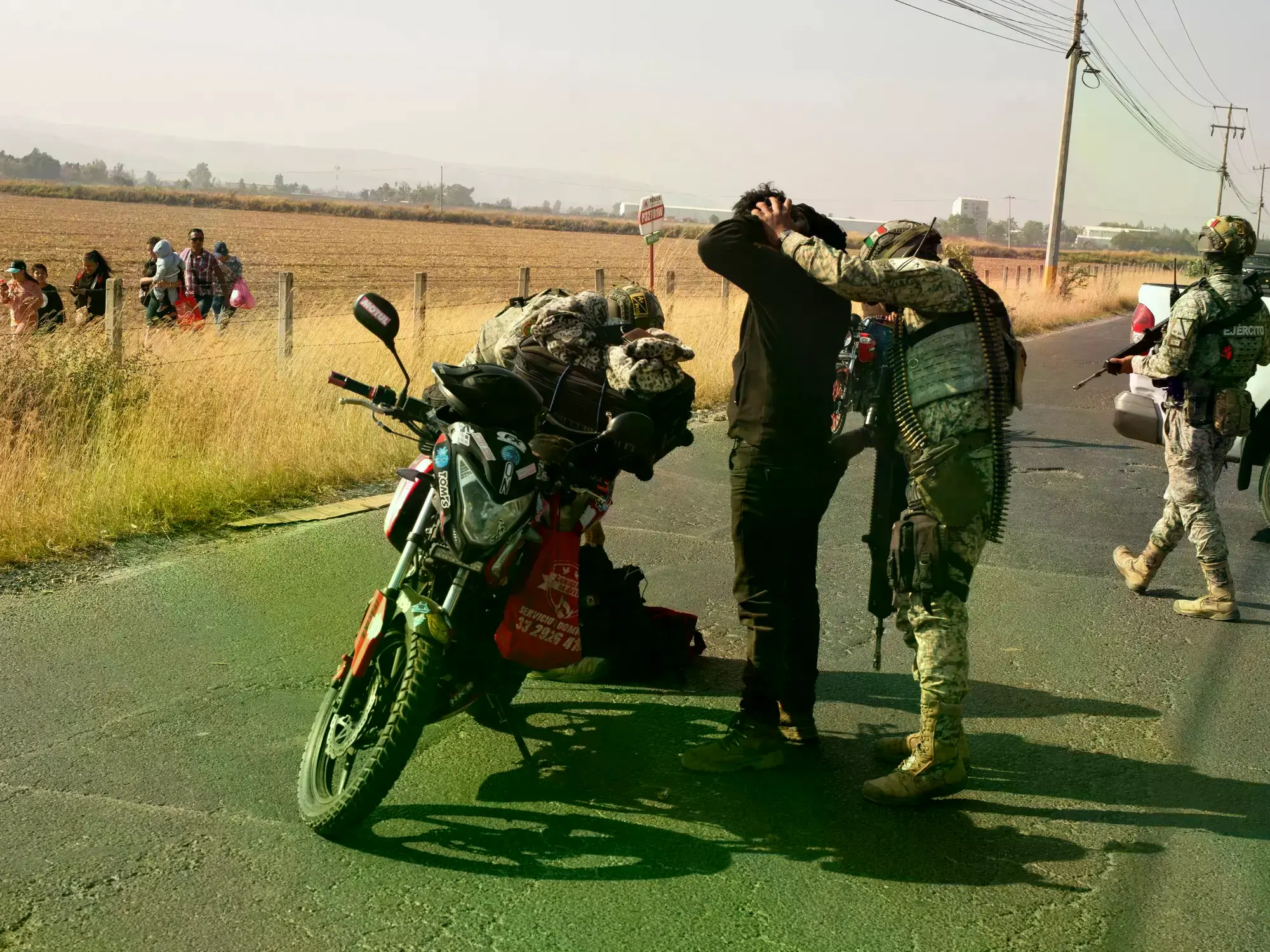 Peatones pasan junto a autobuses calcinados tras bloqueos en Guadalajara, Jalisco.