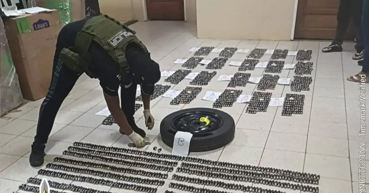 Un funcionario extrae droga oculta de un compartimento del vehículo incautado.