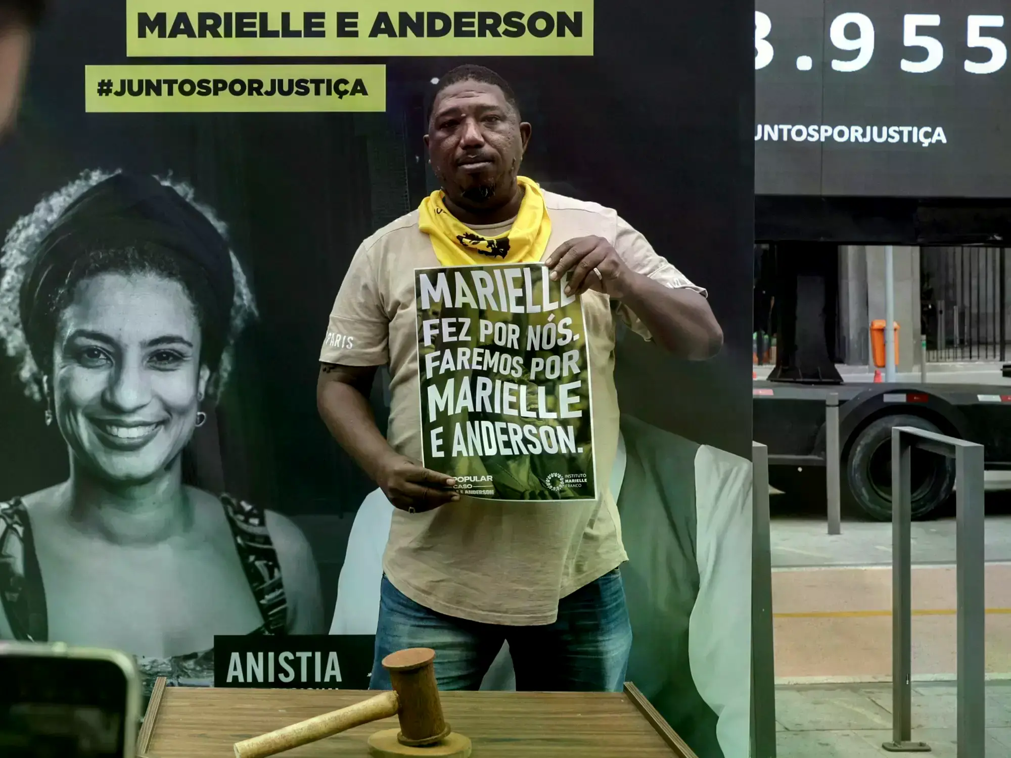Hombre con cartel en apoyo a Marielle Franco afuera del tribunal donde se realizó el juicio.