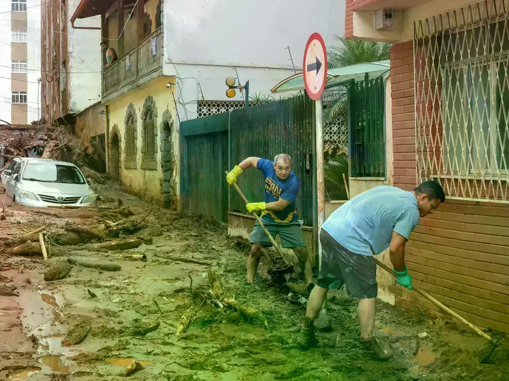 Vecinos de Juiz de Fora tratan de sacar el barro y el agua del frente de sus casas.