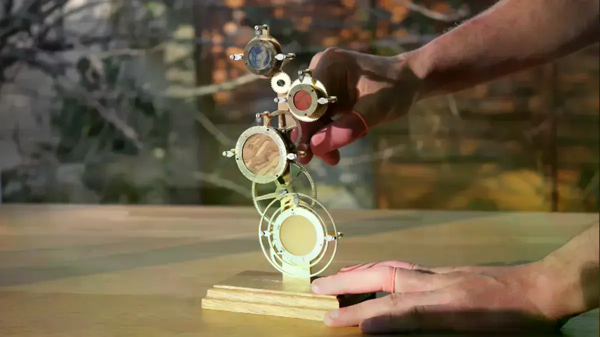 El Reloj Interplanetario, un dispositivo mecánico con engranajes y esferas para varios planetas.