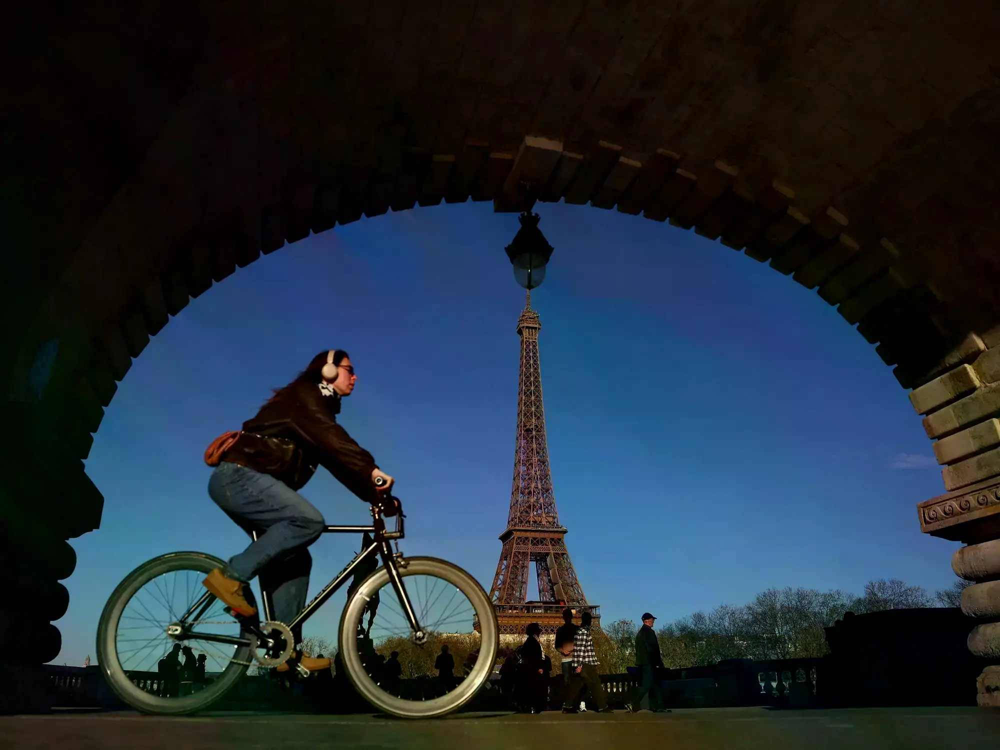 Una mujer en bicicleta cerca de la Torre Eiffel en París.