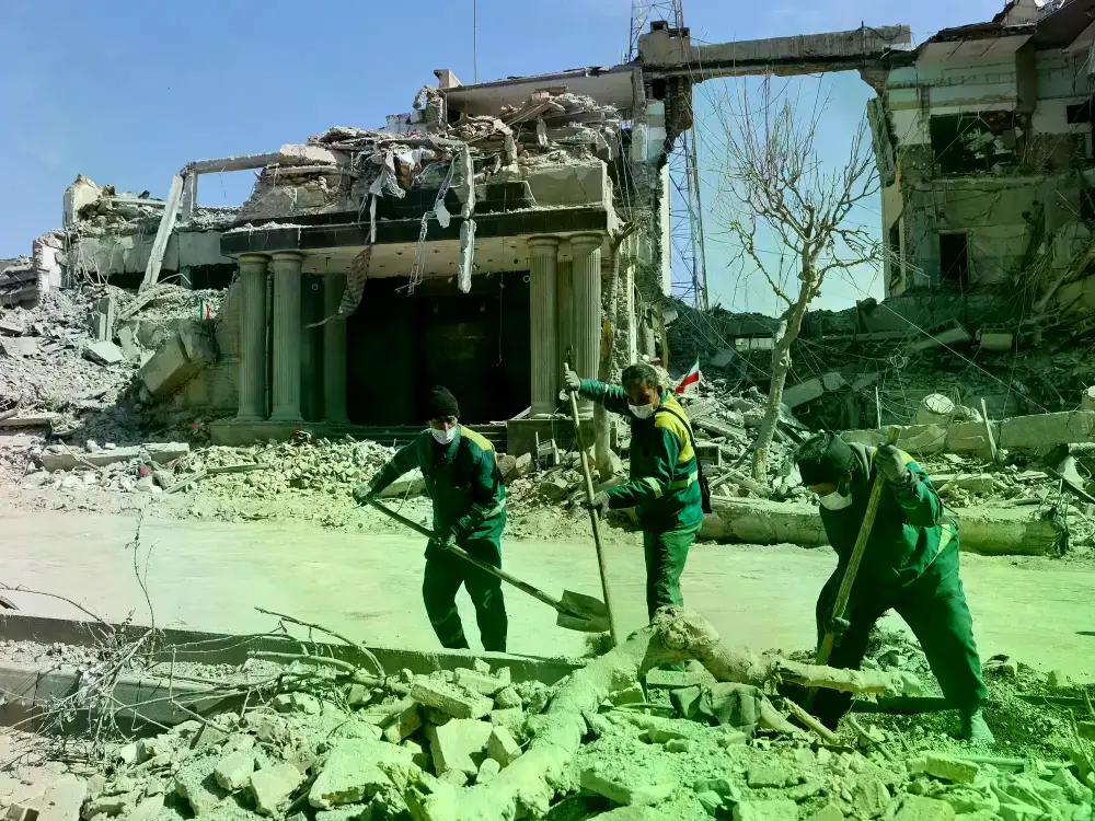 Iraníes pasan junto a edificios bombardeados en Teherán.