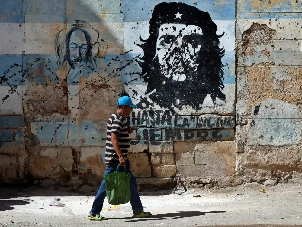 Una persona camina frente a un mural con la imagen de Ernesto 'Che' Guevara en La Habana.