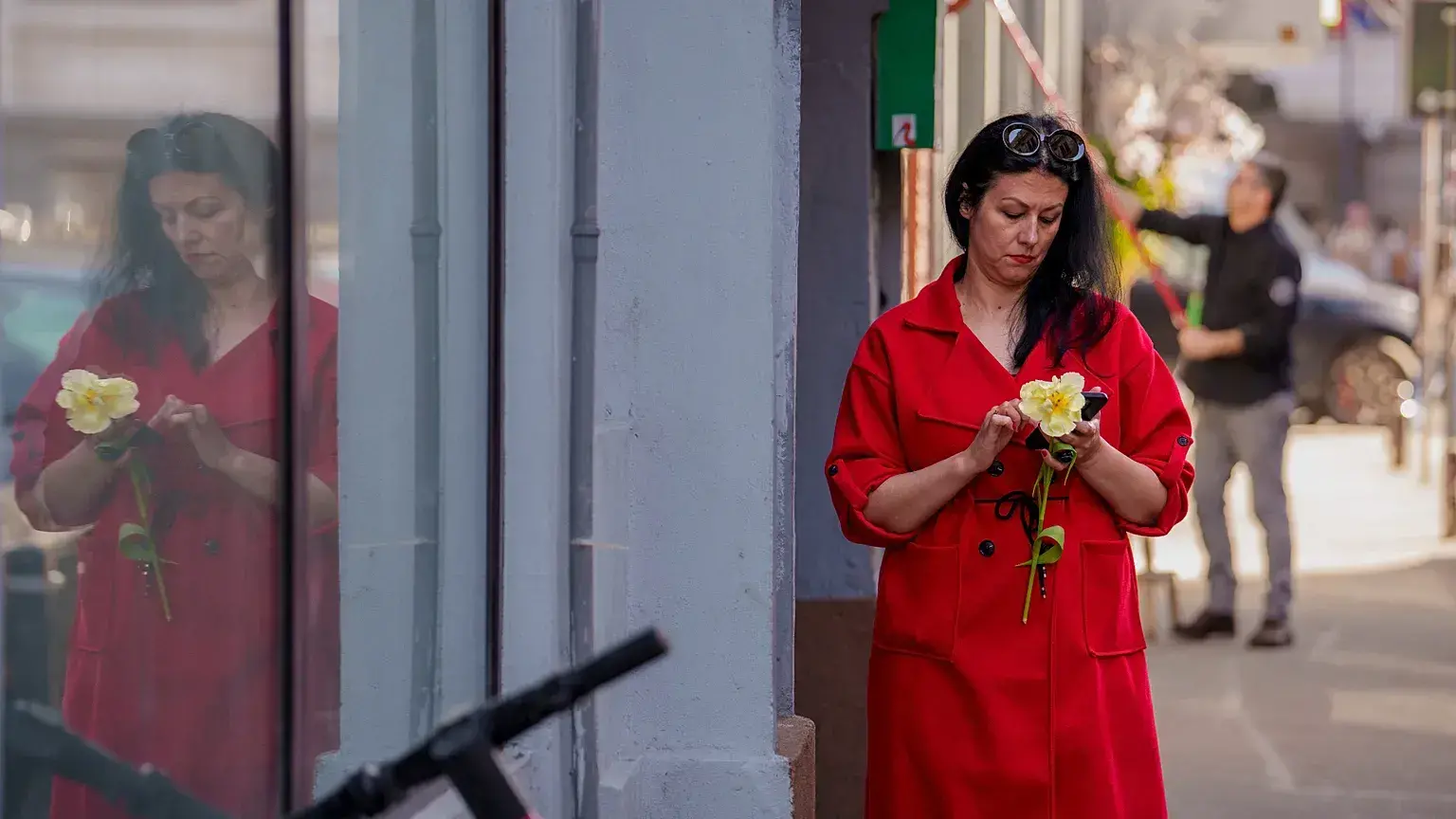Una mujer sostiene una flor mientras mira un teléfono móvil en el Día Internacional de la Mujer en Bucarest (archivo 2025).