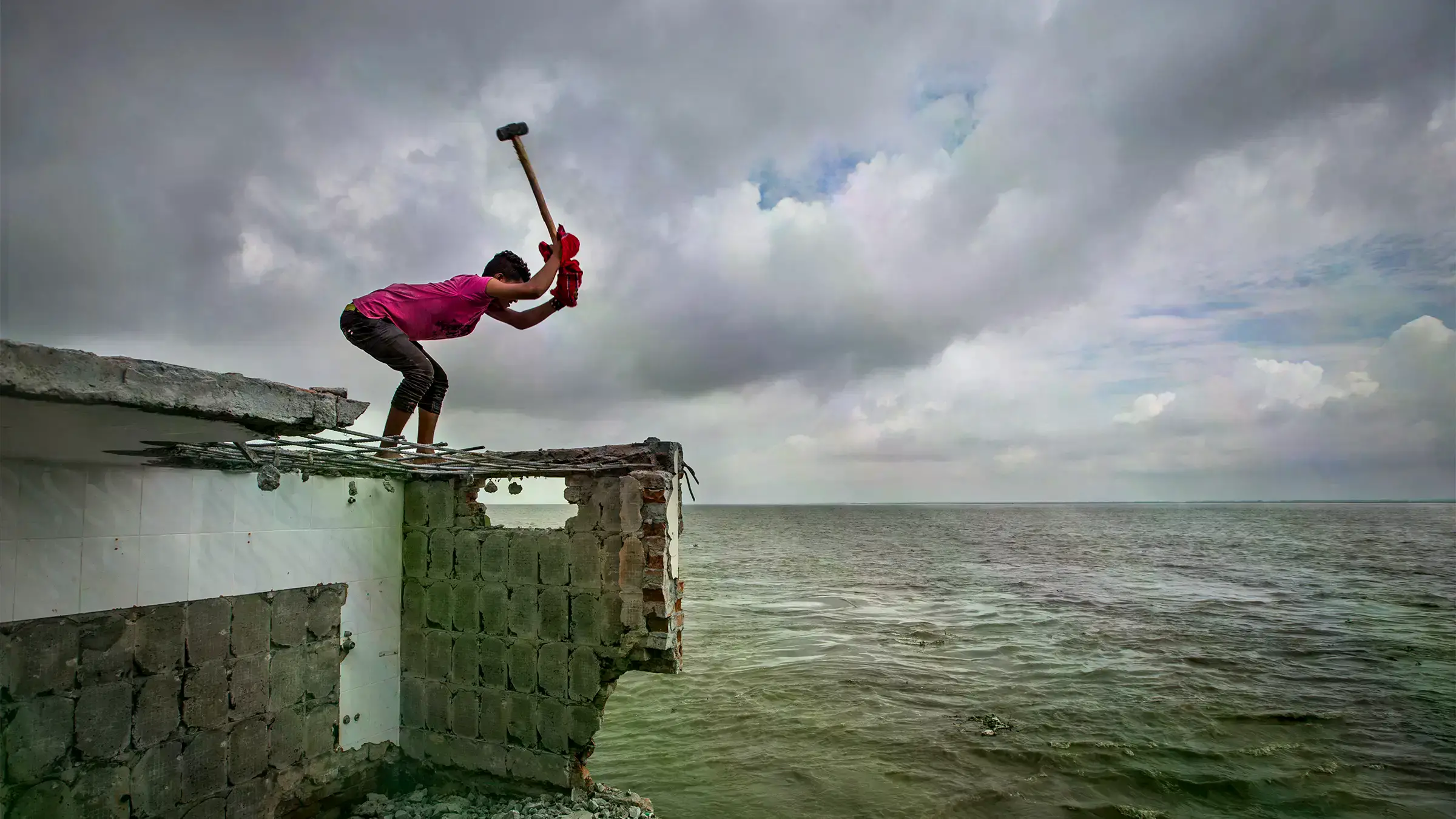 Un hombre desmonta su casa de ladrillos tras una inundación en Shariatpur, 2018.