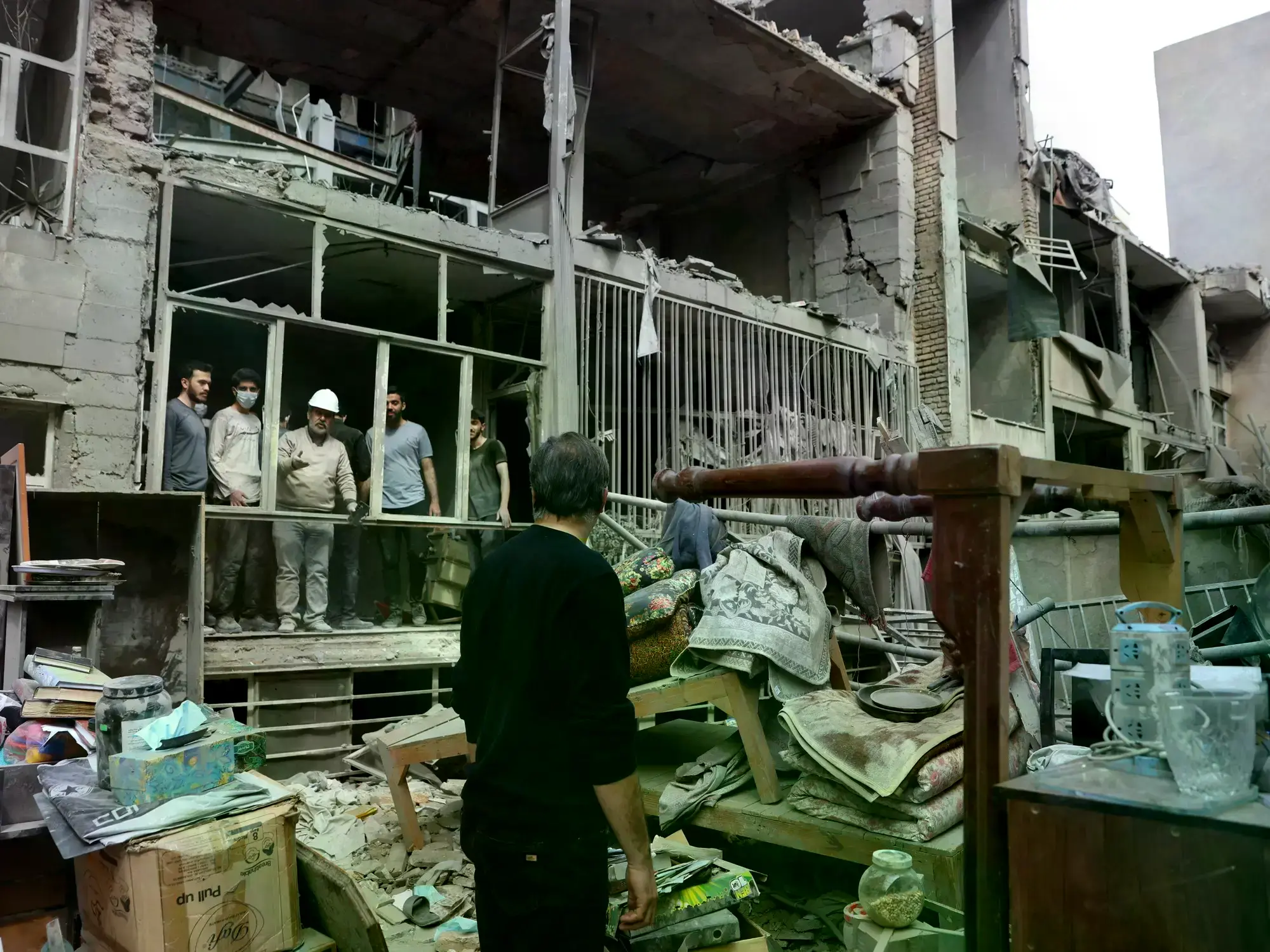 Residentes iraníes recogen sus pertenencias en un edificio dañado en el sur de Teherán.