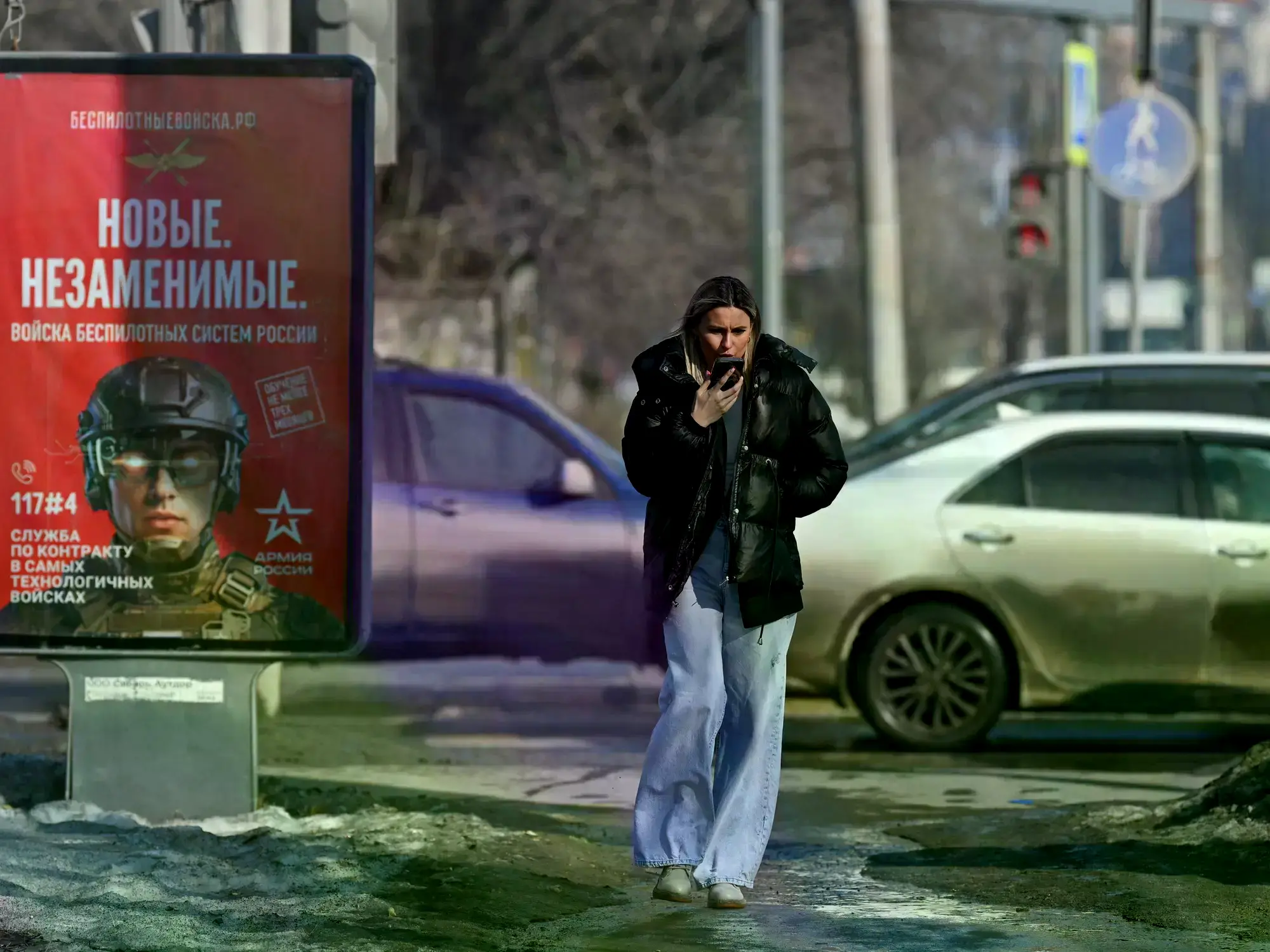 Una mujer pasa junto a un cartel publicitario que promociona el servicio militar por contrato en las fuerzas de sistemas no t