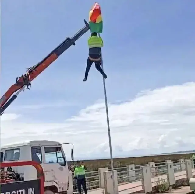 Un policía, con ayuda de una grúa del Ejército, retira la bandera boliviana.