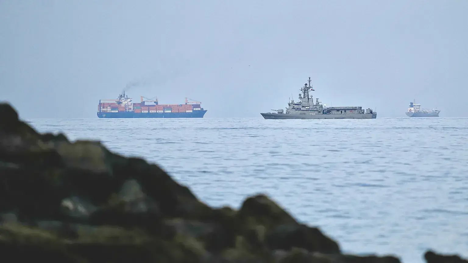 Un buque de la marina de los EAU navega junto a un carguero en el estrecho de Ormuz, visto desde Khor Fakkan, Emiratos Árabes