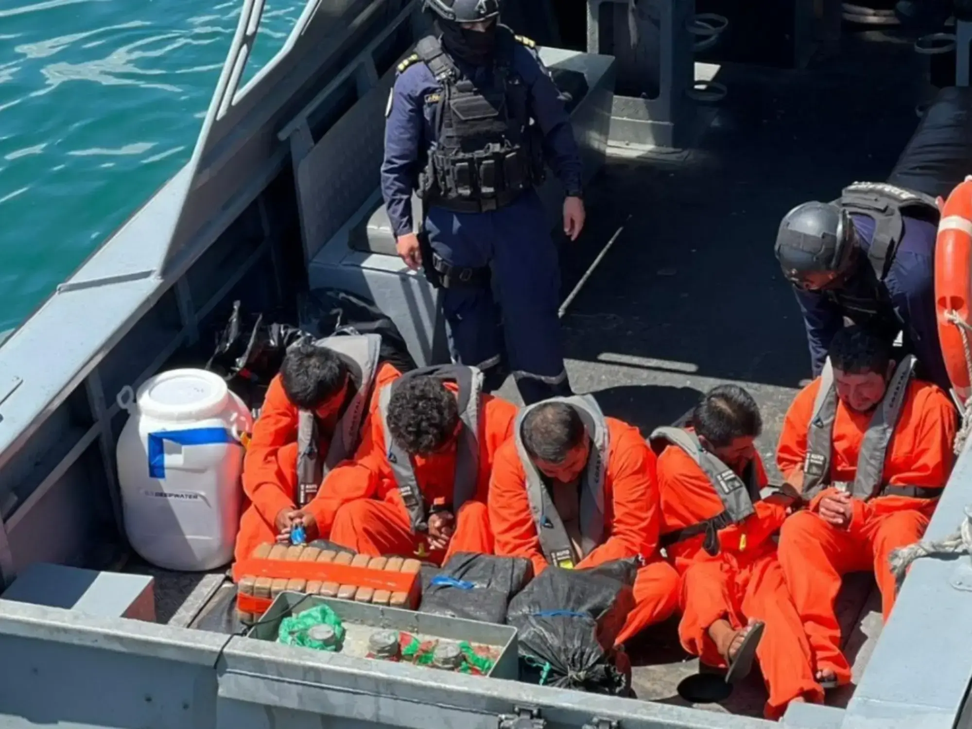 Detenidos con mamelucos naranjas sobre una lancha intervenida.