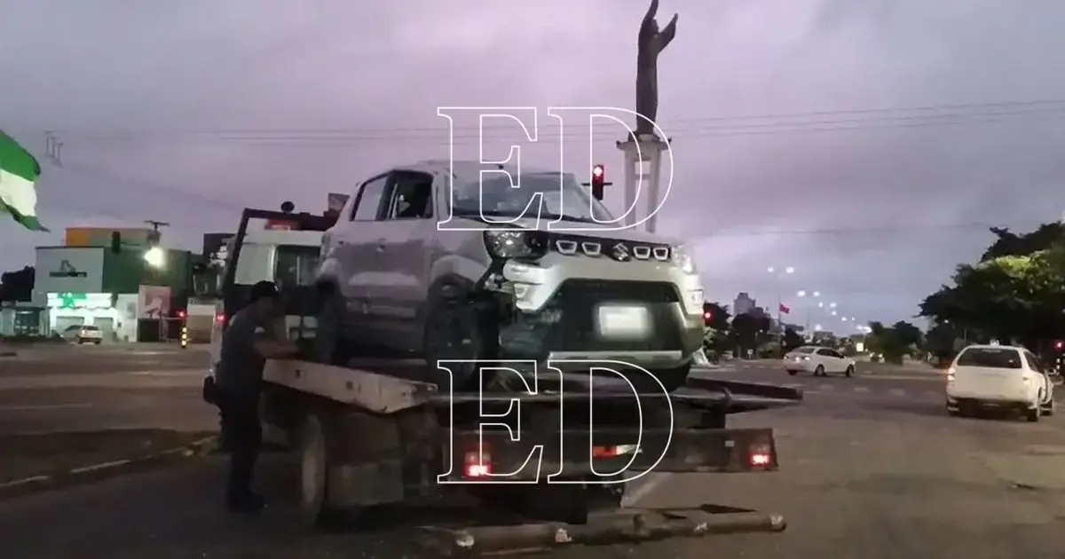 Vehiculo accidentado volcado junto a un arbol en la acera.