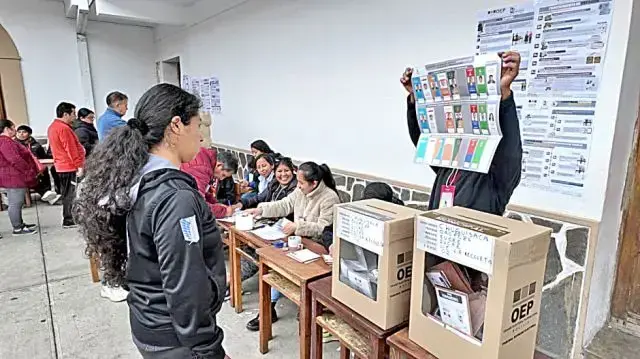 Un jurado electoral enseña la papeleta a una ciudadana en el recinto de La Recoleta.