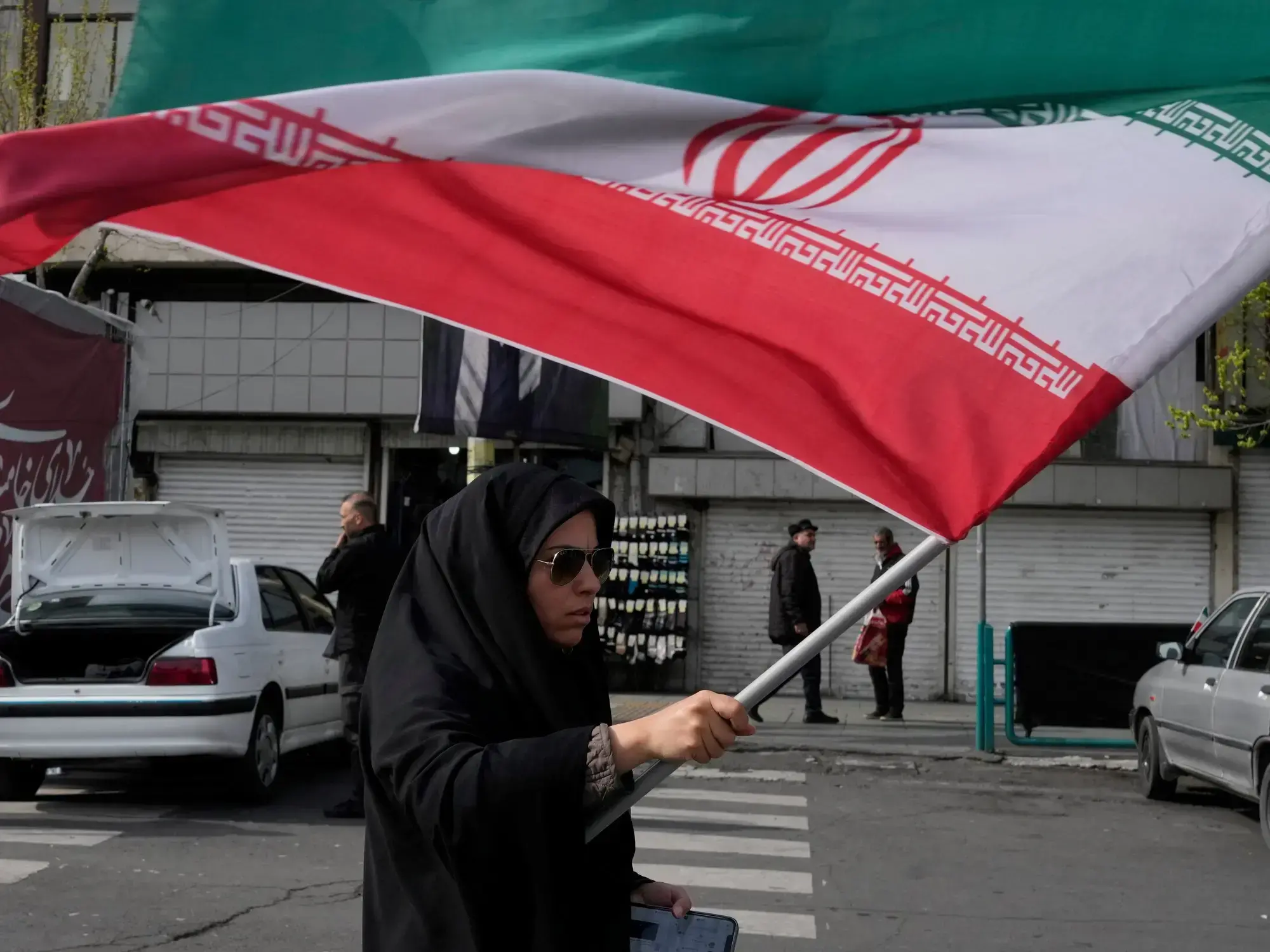 Una mujer marcha con una bandera de Irán en Teherán.