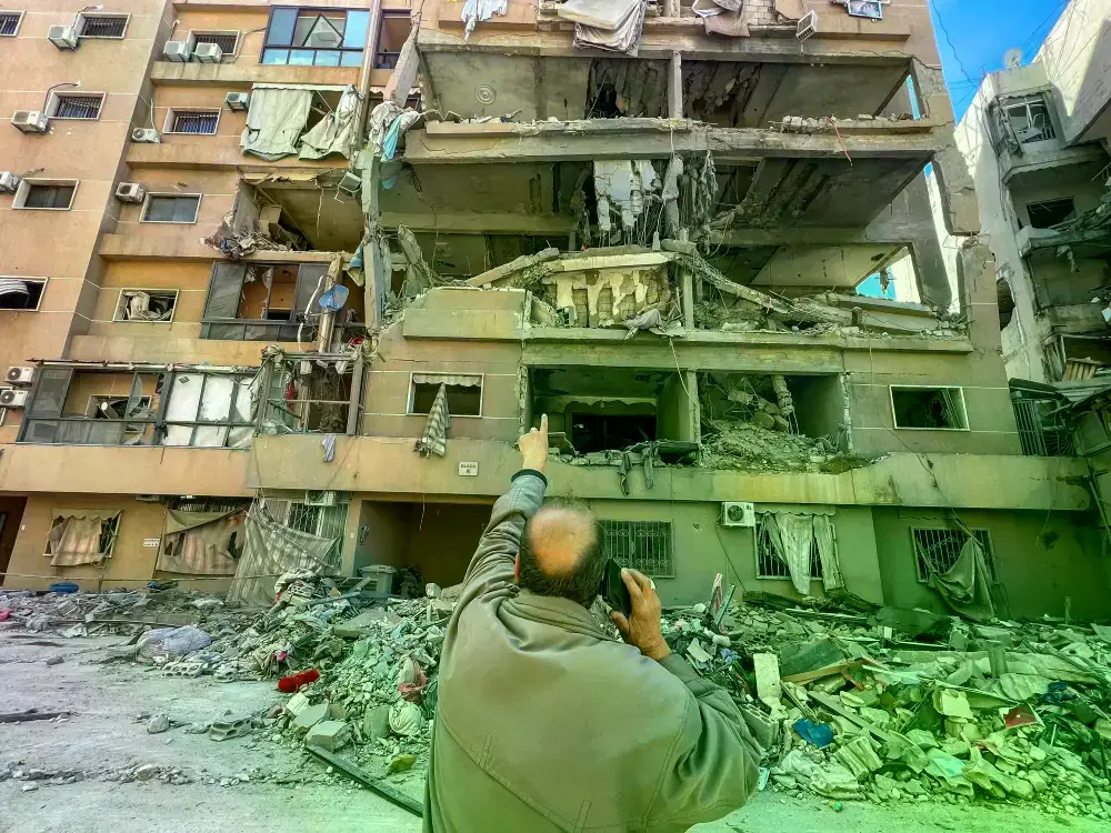 Un hombre señala un edificio dañado por ataques israelíes en los suburbios del sur de Beirut.