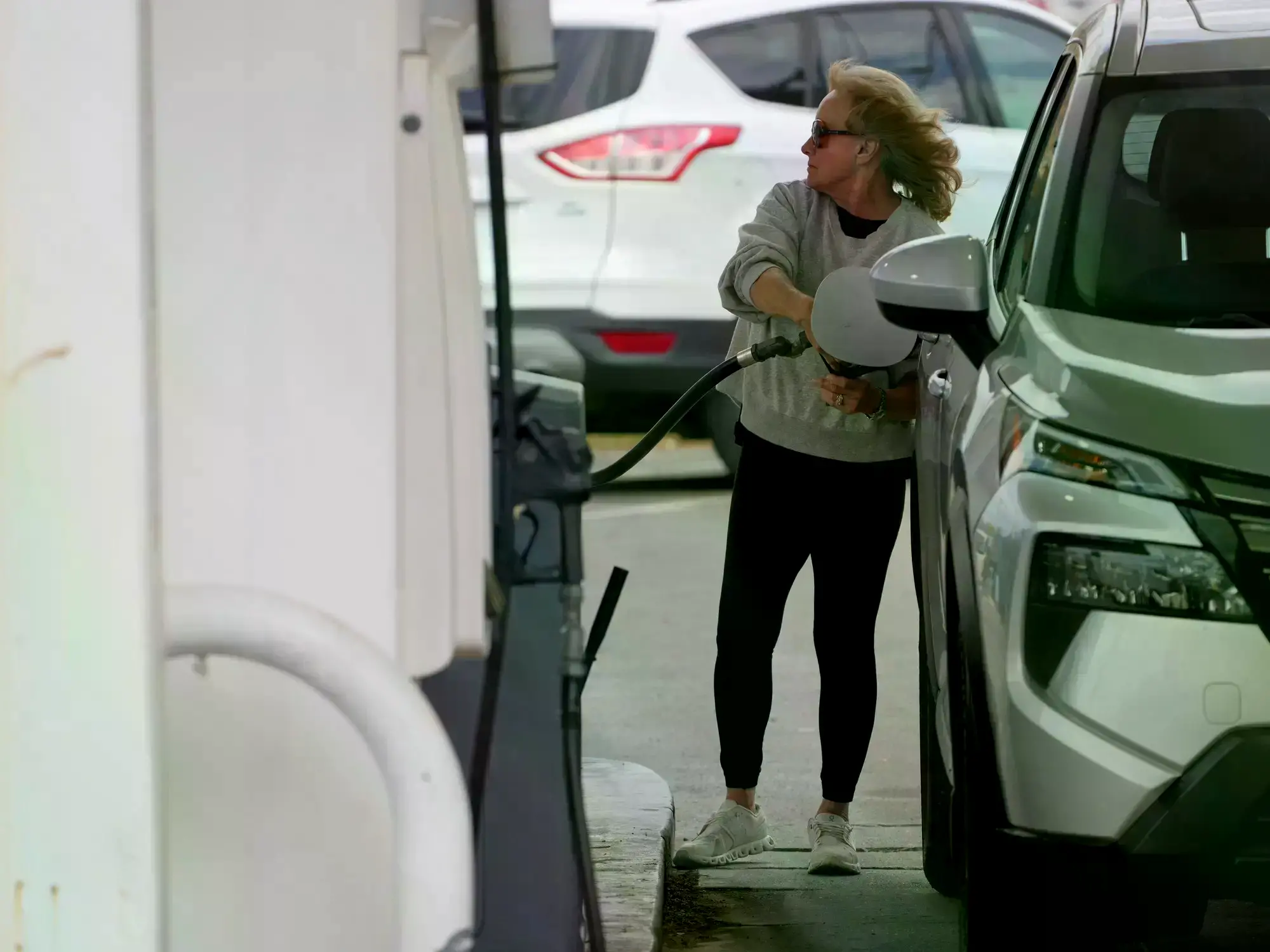 Una mujer llena el tanque de combustible en una gasolinera.