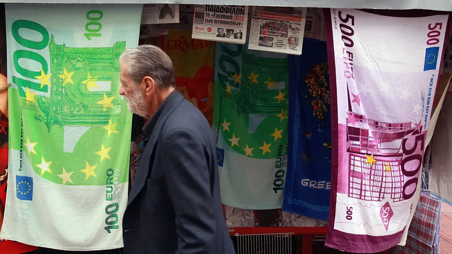 Un hombre pasa junto a un quiosco que vende toallas impresas con billetes de euro en Atenas.