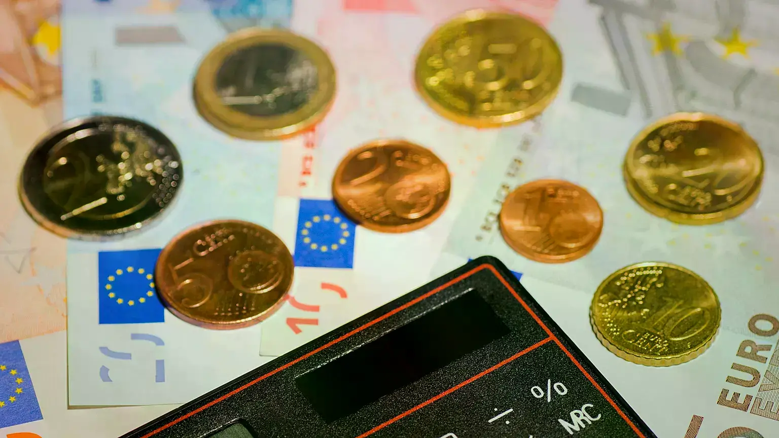 Fotografía de stock de dinero, una calculadora y una casa de juguete.