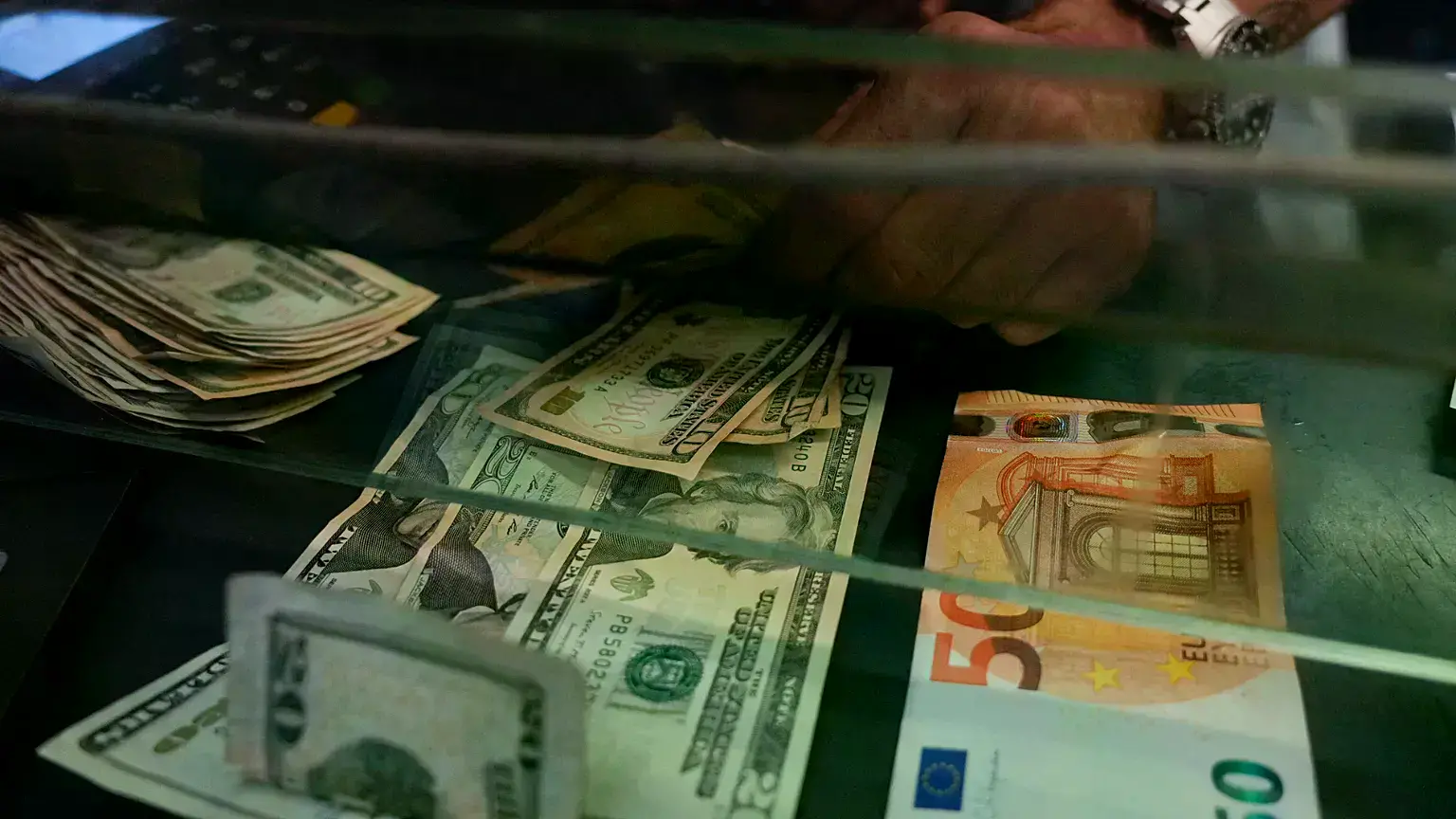 Una cajera cambia un billete de 50€ por dólares estadounidenses en una casa de cambio.