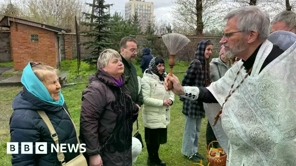 Personas hacen cola para ser rociadas con agua bendita por un sacerdote en Kharkiv.
