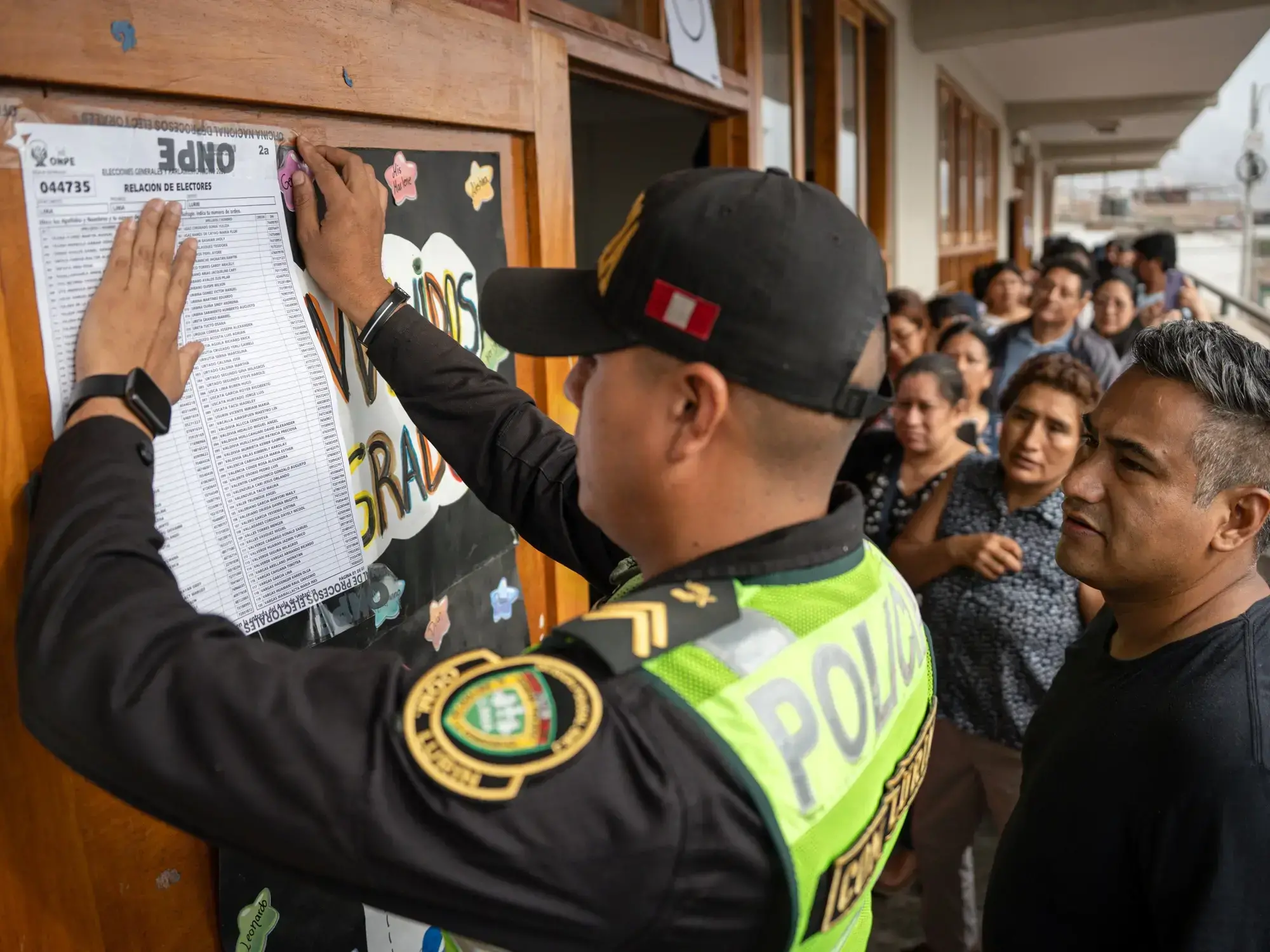 Un policía pega un cartel afuera de un aula de votaciones en el colegio Señor de los Milagros en Lurín.