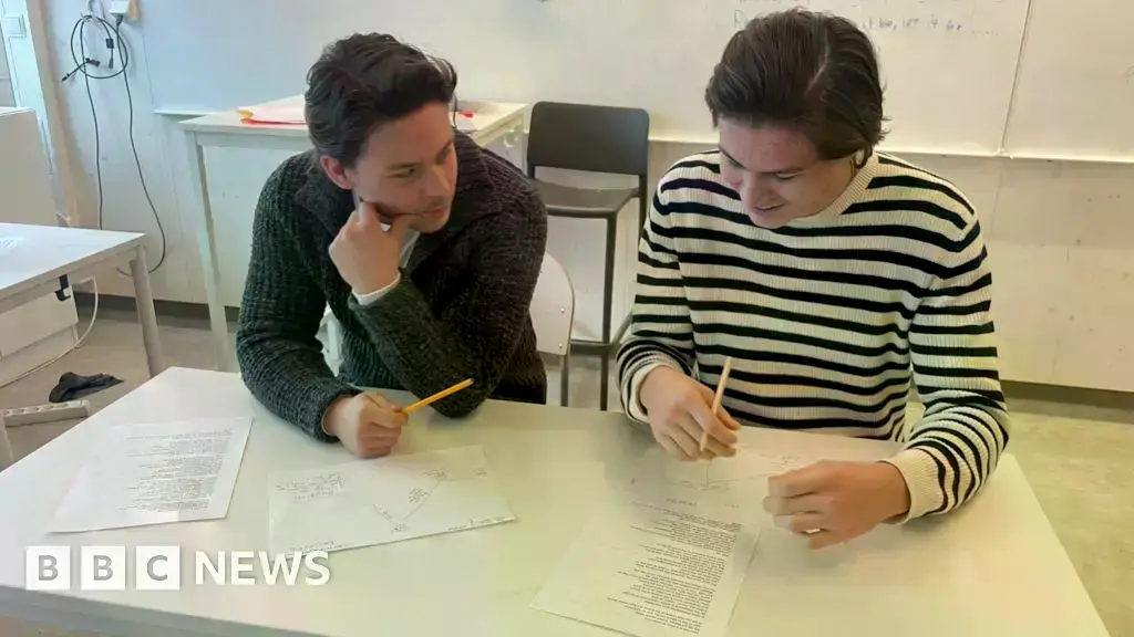 Un estudiante sueco sostiene un libro de texto en un aula.