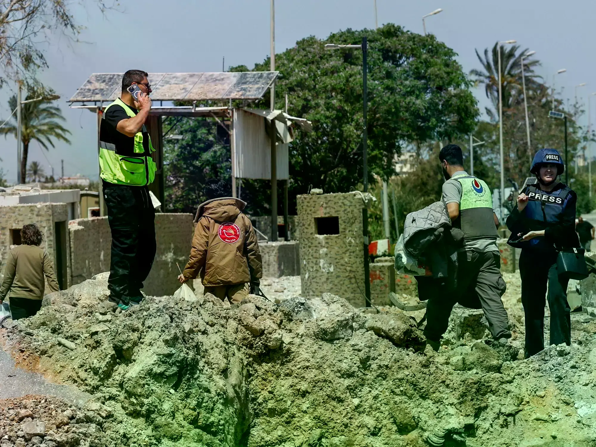 Personal de emergencia trabaja entre los escombros de un puente fronterizo destruido por un bombardeo israelí.