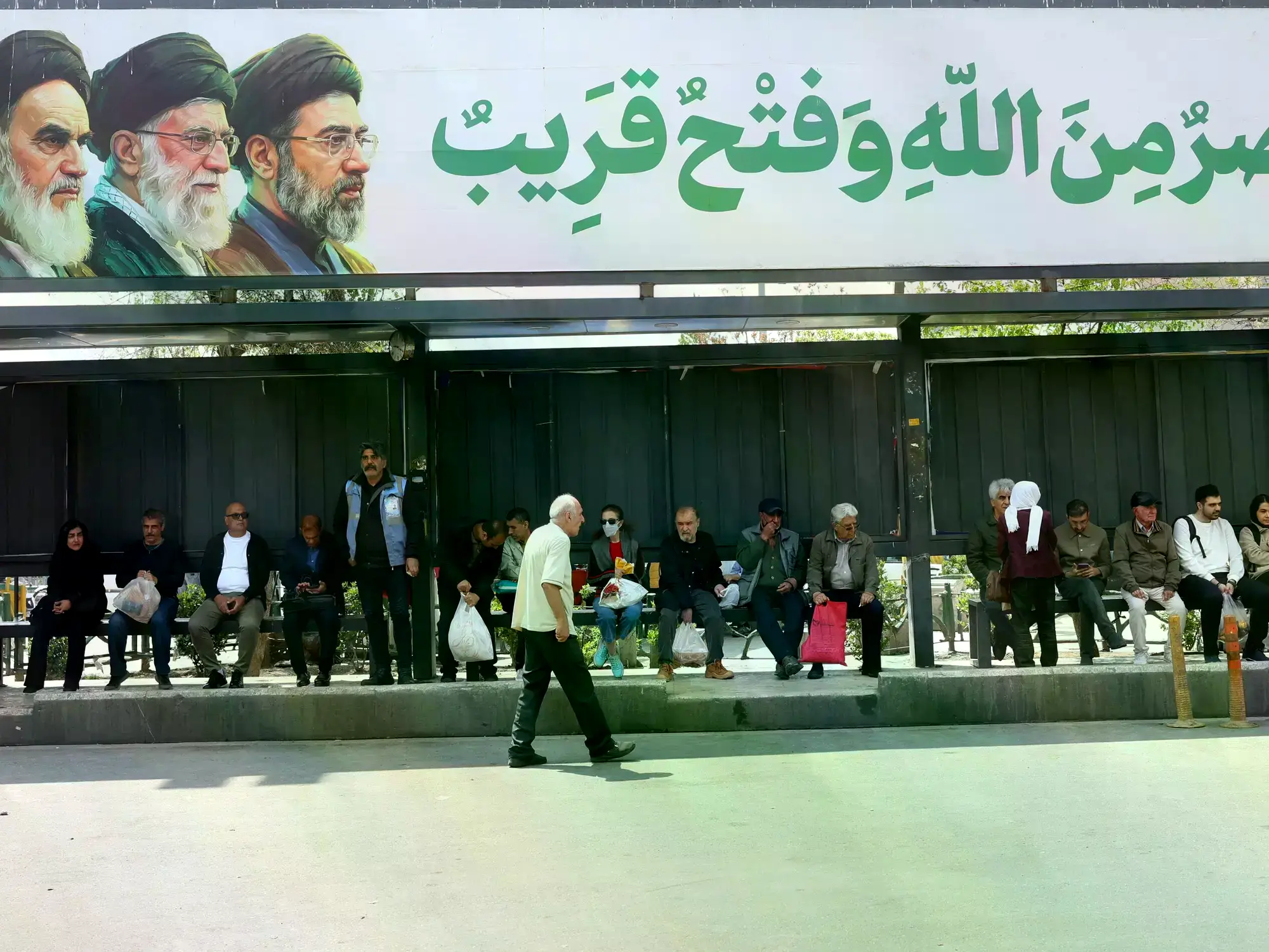 Un cartel con la imagen de los líderes iraníes en una parada de colectivos en Teherán.