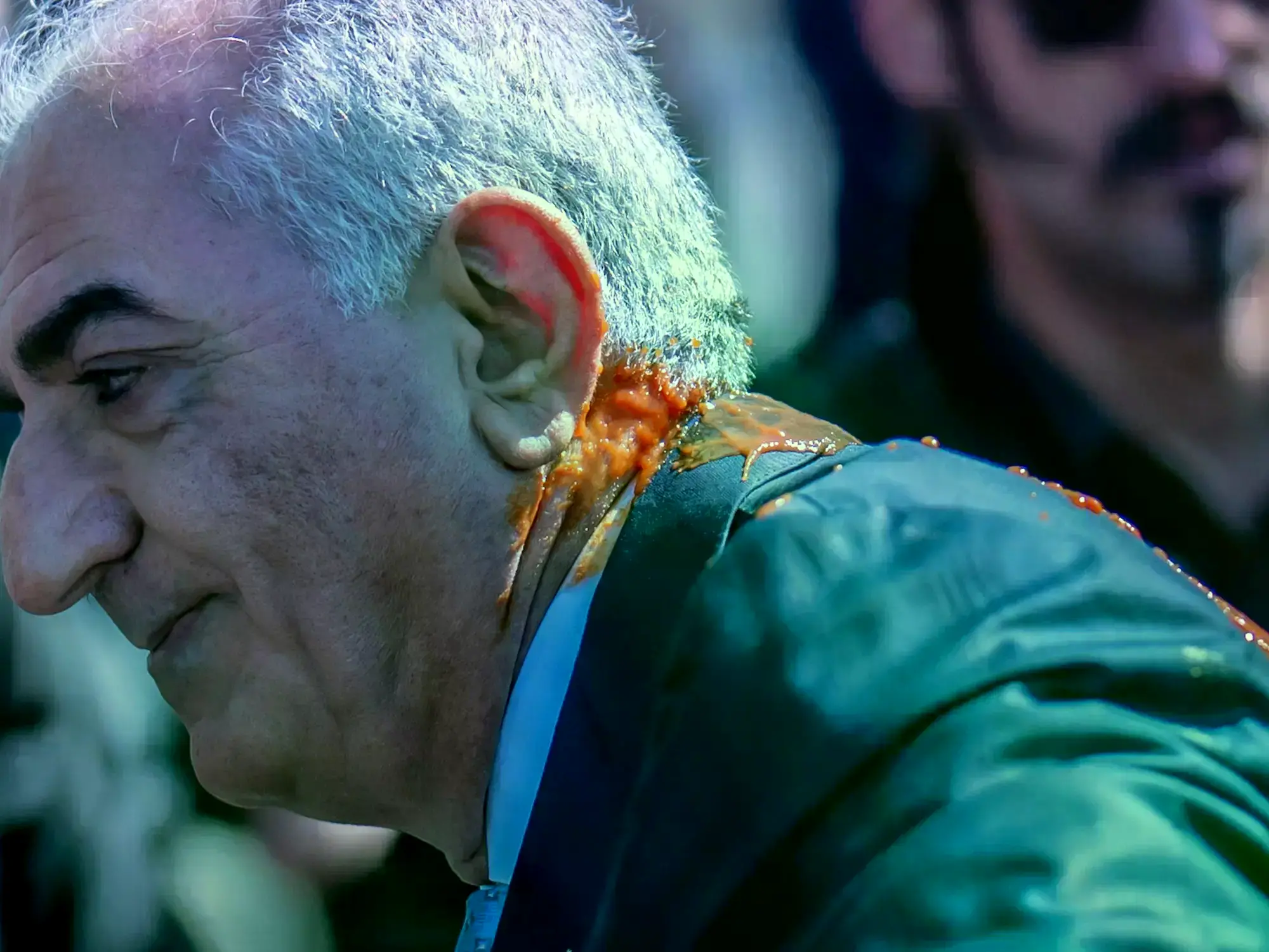 Reza Pahlavi, con su cuello y espalda manchados por el líquido rojo que le arrojaron en Berlín.