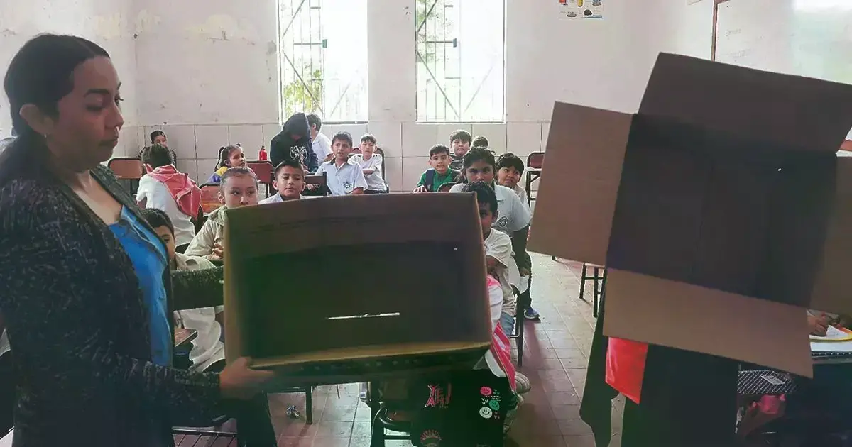 Una maestra del colegio Ángel Chávez Gutiérrez muestra las cajas vacías del alimento complementario.