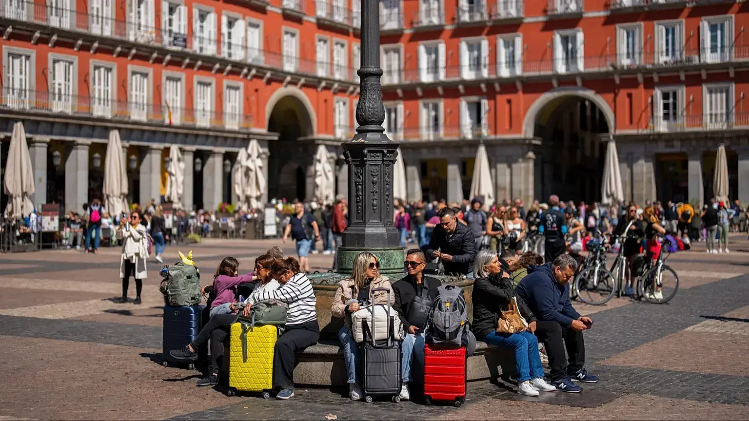 Turistas sentados en un banco público en la Plaza Mayor, en el centro de Madrid, España.