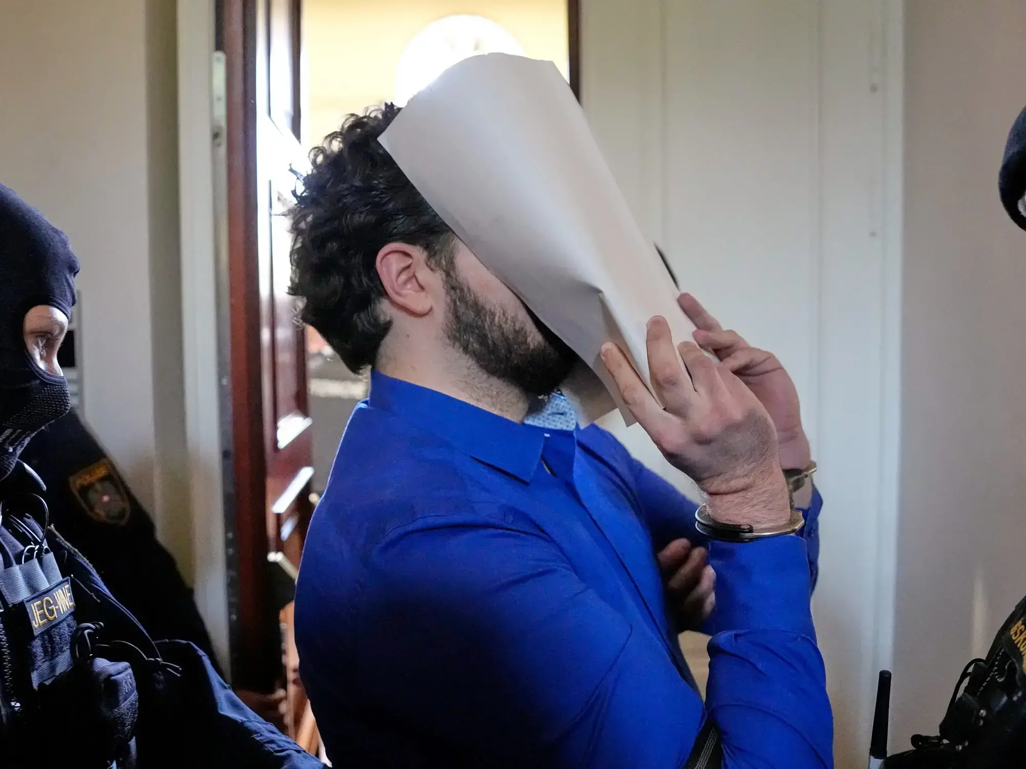 Beran A., el acusado de intentar atentar contra un show de Taylor Swift, se cubre la cara al llegar al tribunal.