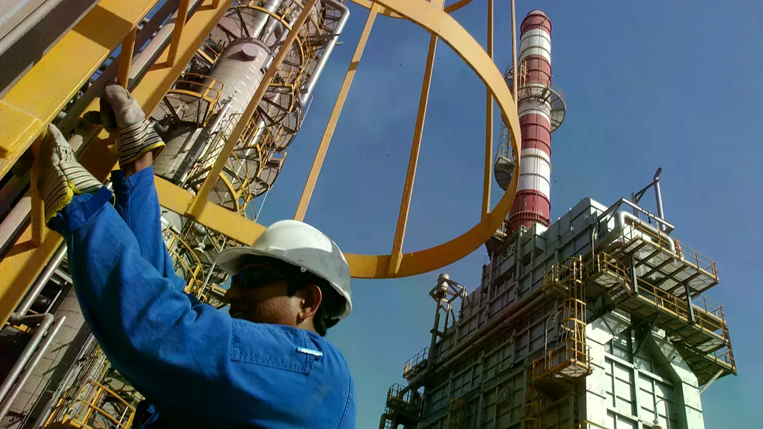 Un técnico petrolero desciende por una torre en una refinería de Jebel Ali, Emiratos Árabes Unidos, marzo de 2004