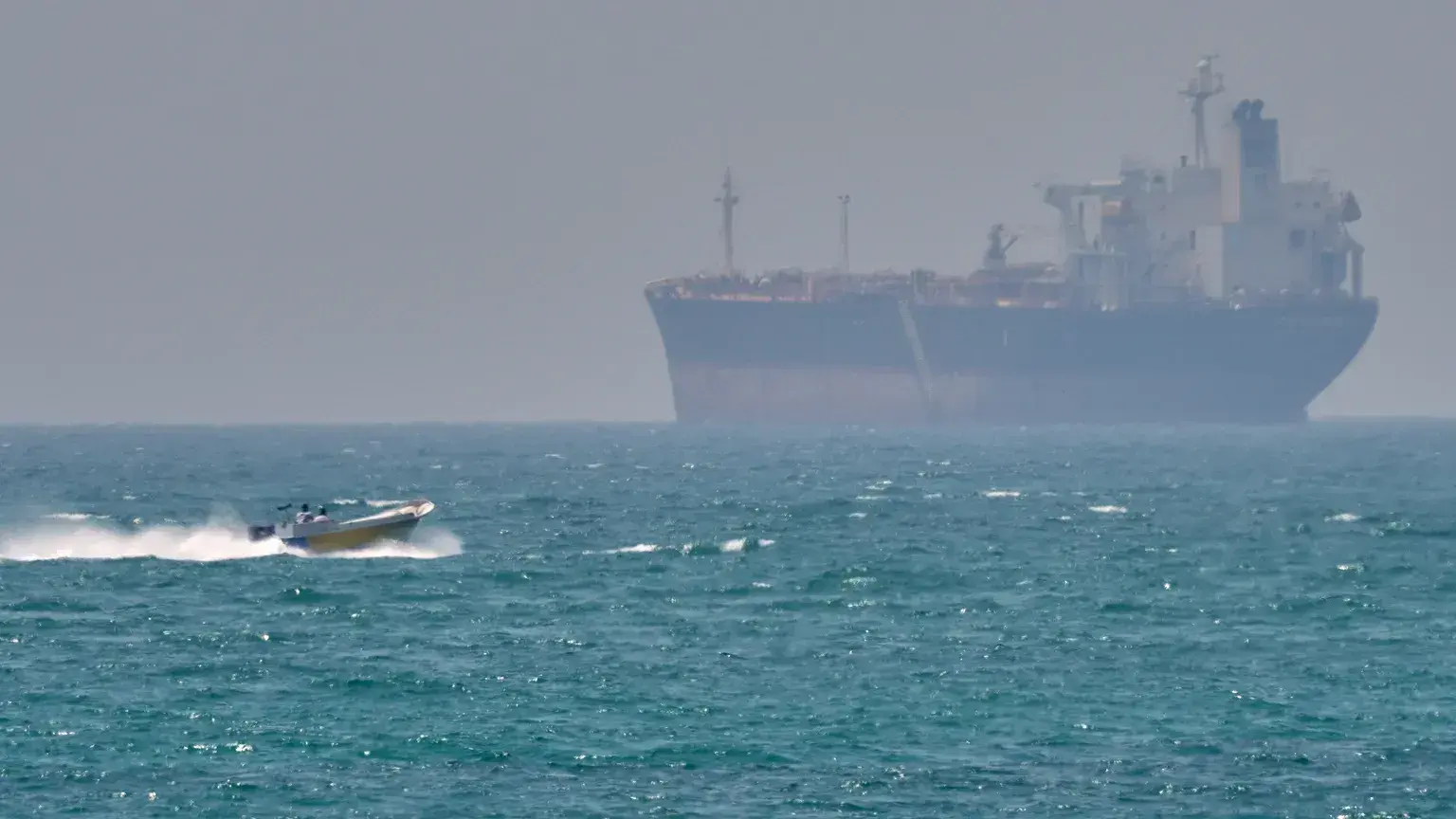 Un barco pasa junto a un petrolero anclado en el estrecho de Ormuz, frente a la costa de la isla de Qeshm, Irán, el 18 de abr