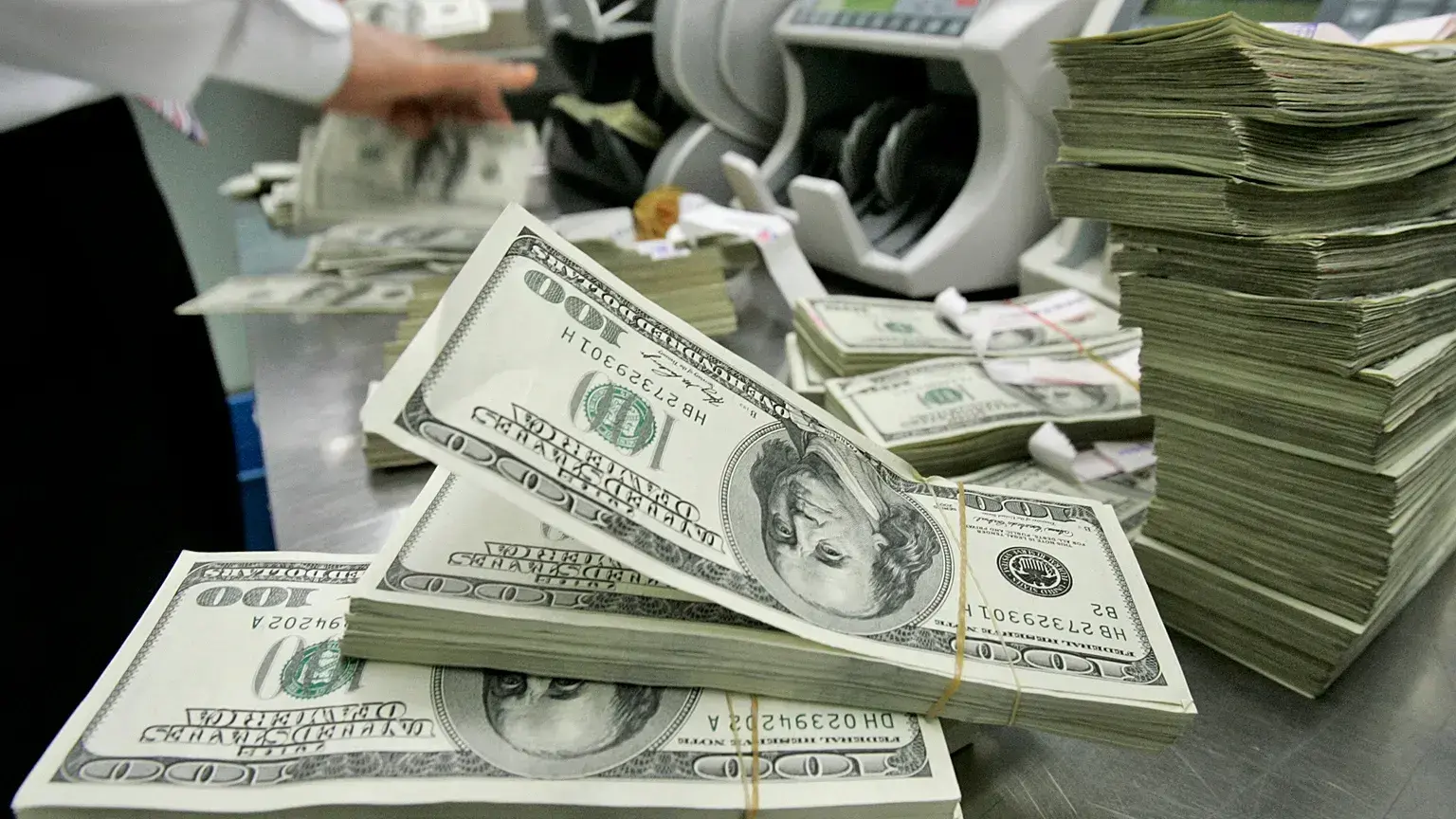 Un empleado de banco surcoreano trabaja junto a fajos de billetes estadounidenses en la sede del Korea Exchange Bank en Seúl