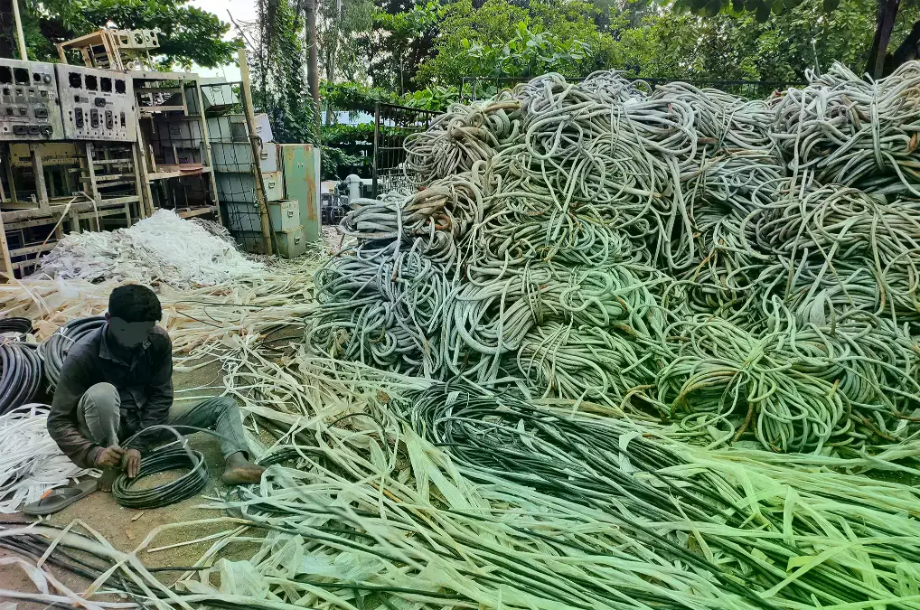 Trabajador separa cubiertas de plástico de cables recuperados de barcos desguazados en Chattogram.