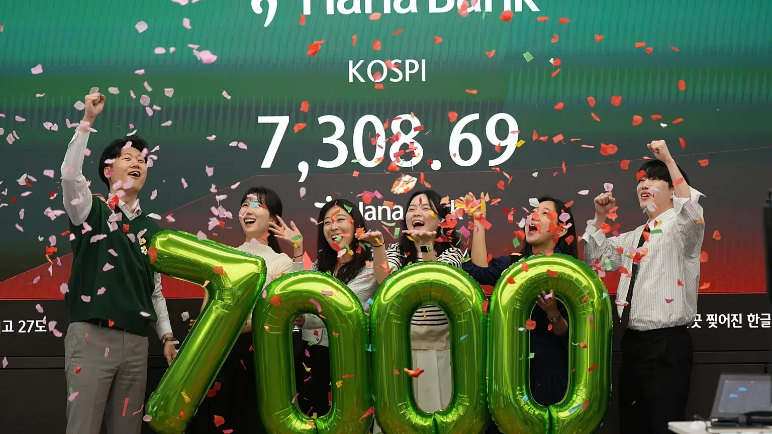 Empleados de Hana Bank celebran que el KOSPI supera los siete mil puntos, en Seúl, 6 de mayo de 2026.