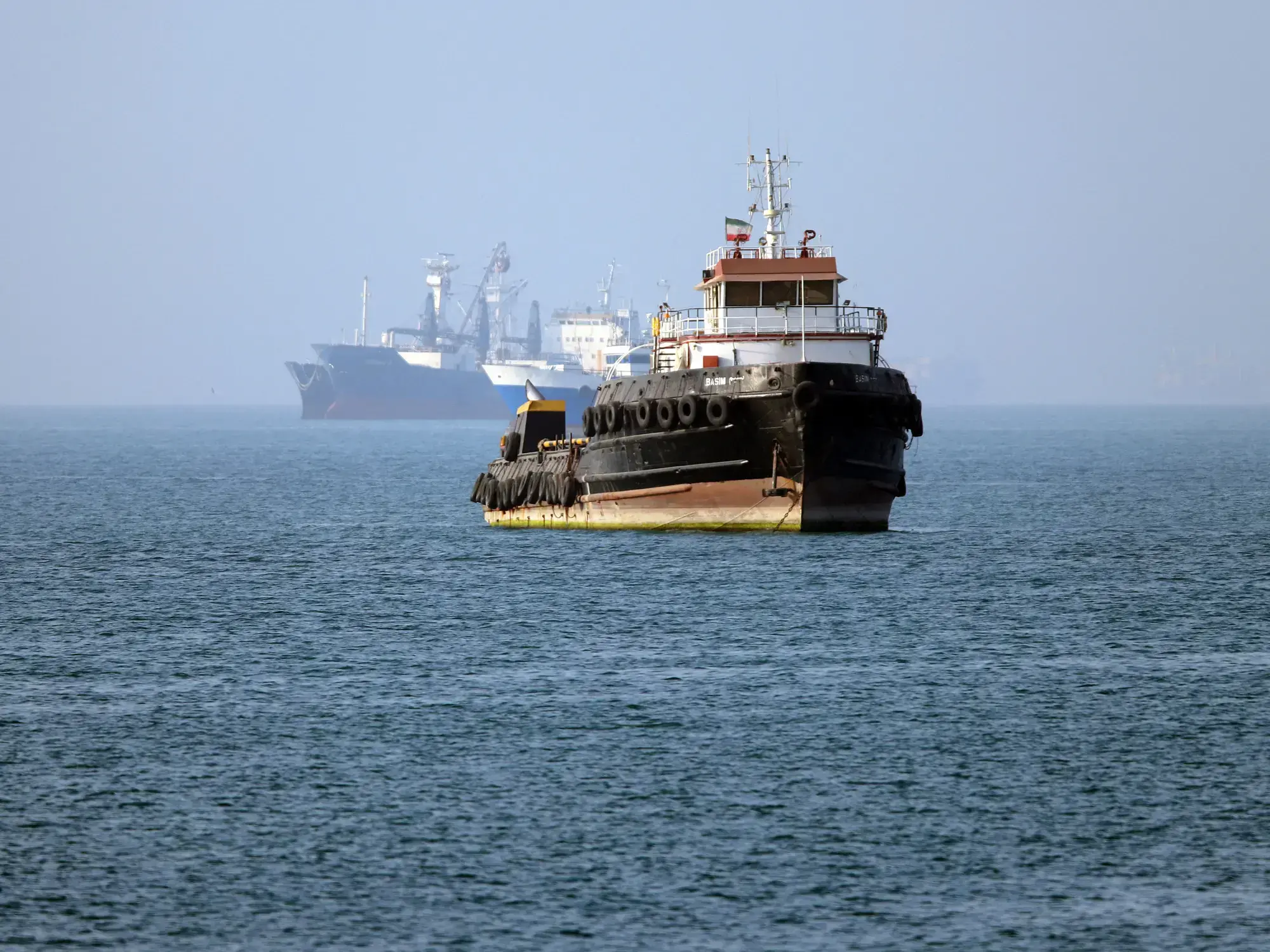 El remolcador Basim, con bandera iraní, navega cerca de un barco anclado en el estrecho de Ormuz, frente a Bandar Abbas, en e