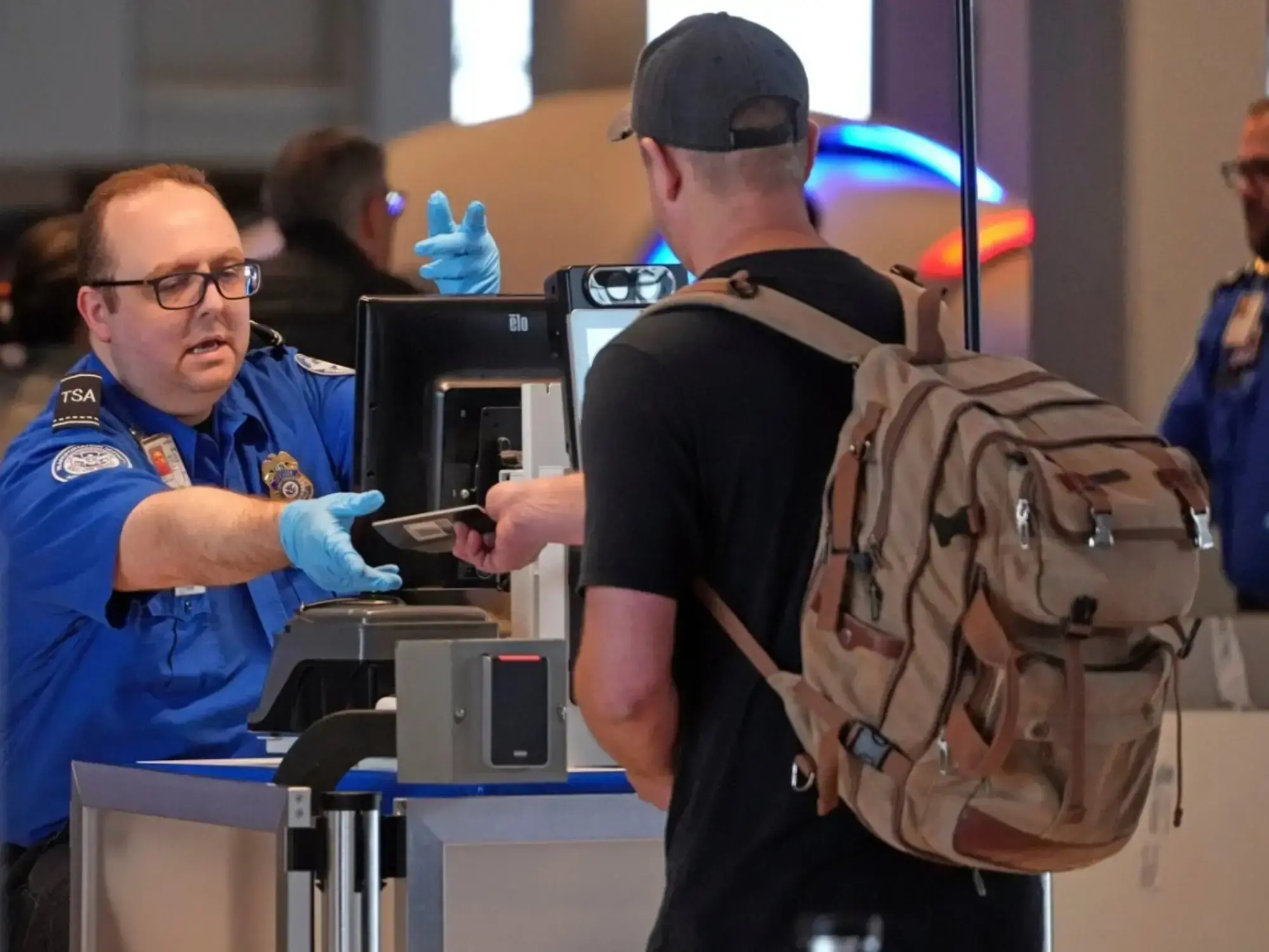 Un empleado de la TSA devuelve el pasaporte a un viajero en Pittsburgh.