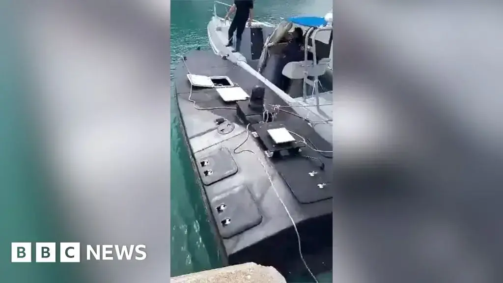 Momento en que el dron naval descubierto (izquierda) es remolcado por un guardacostas griego al puerto de Vasiliki.
