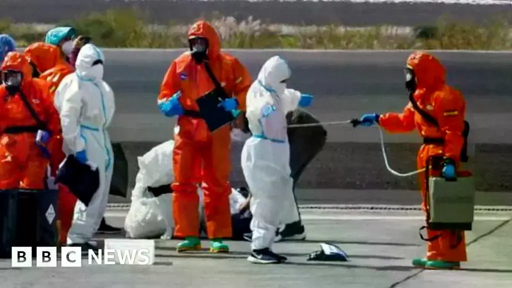 Pasajeros del crucero MS Hondius son rociados con desinfectante al llegar al aeropuerto de Tenerife.