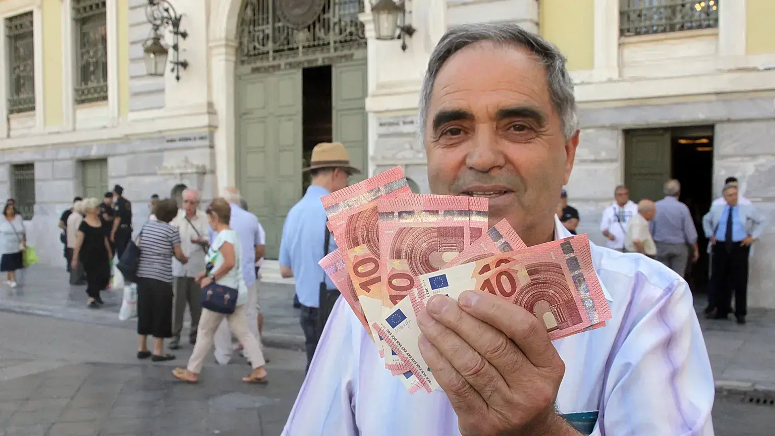 El pensionista Giorgos Petropoulos muestra billetes de diez euros que recibió del Banco Nacional de Grecia en Atenas, el miér